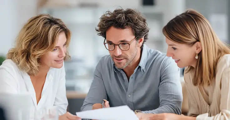 Drei Personen im Gespräch über Immobilienverkauf